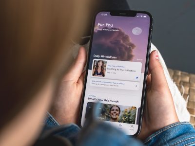 a woman holding a cell phone with a facebook page on it